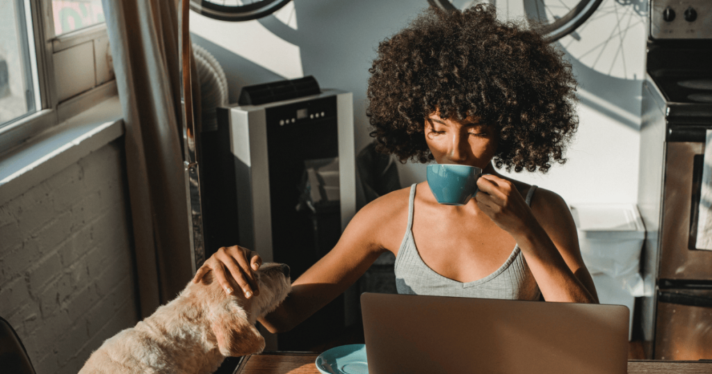 A woman working remotely at home while petting her dog.
